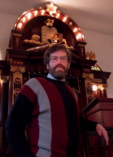 [ Jordan Lee Wagner, standing before the Ark in the historic Adams Street Shul in Newton Massachusetts ]